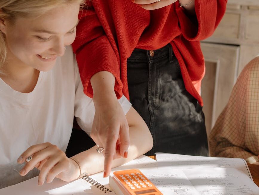 girl in white crew neck t shirt writing on white paper