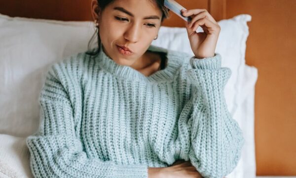 woman with credit card pondering while buying online with laptop
