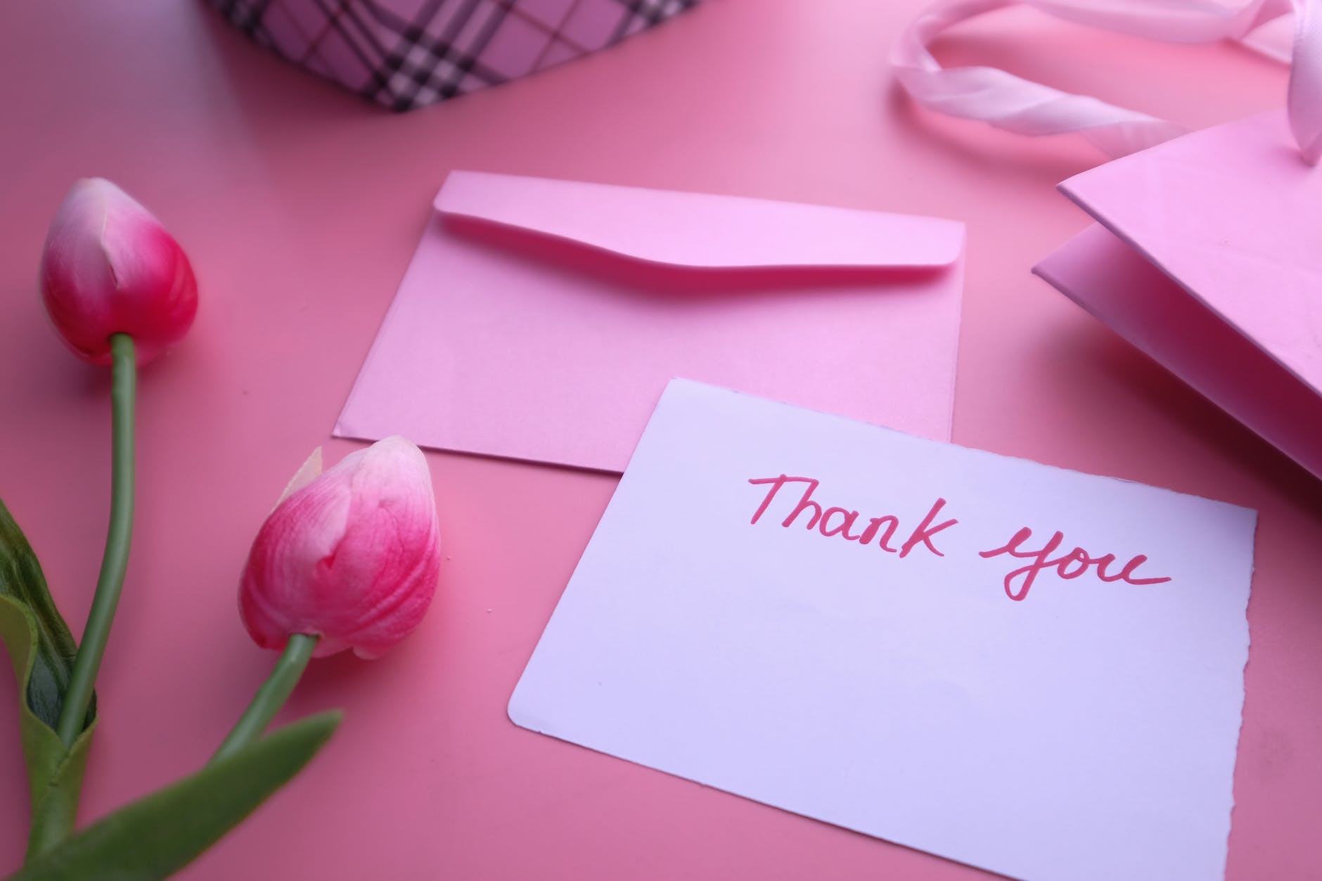 a thank you letter near the pink flowers and envelope