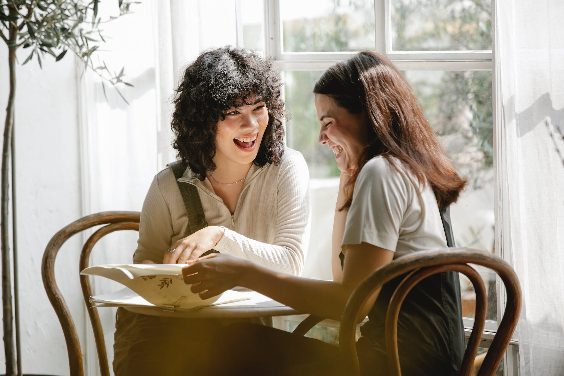 cheerful diverse girlfriends reading document at table