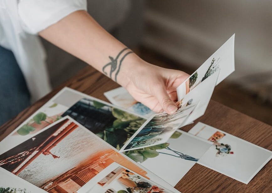 crop unrecognizable woman looking through printed photos