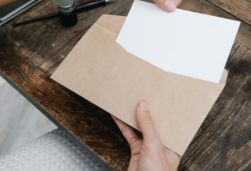 crop unrecognizable woman placing blank paper in envelope